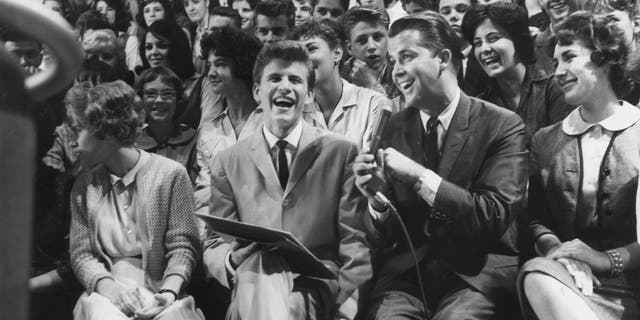 Singer and musician Bobby Rydell sits next to host Dick Clark in the audience of "Amerikaanse Bandstand" rondom 1958. Rydell sang popular songs such as "Volare" and appeared in the hit film "Bye Bye Birdie."