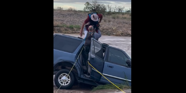 A first responder is seen helping a man put a harness on after he became trapped in floodwaters while trying to cross the Felix River in New Mexico on Saturday, Aug. 20. 