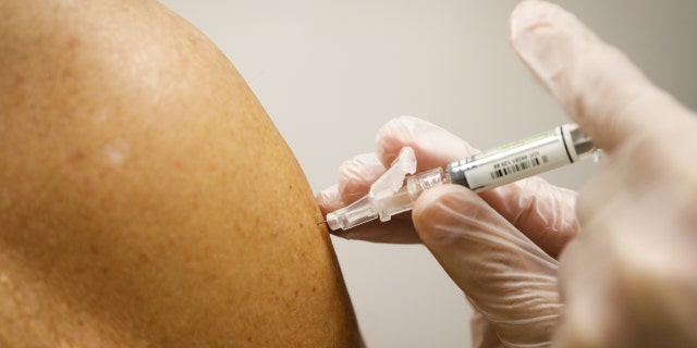 A pharmacist administers a free flu shot vaccine to a customer at a CVS Health Corp. Pharmacy in Miami, Florida, U.S., on Wednesday, Sept. 30, 2020. CVS Health Corp. said this month that it expects to vaccinate up to 18 million people. 