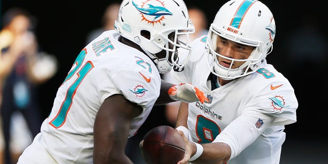 Brock Osweiler, #8 of the Miami Dolphins, hands off to Frank Gore, #21, in the fourth quarter against the Chicago Bears at Hard Rock Stadium on October 14, 2018 in Miami. 