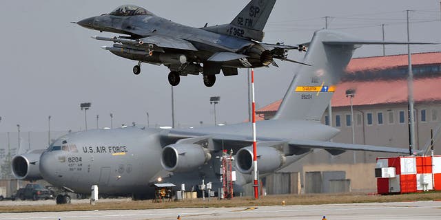 An F-16 lands in front of a C-17 at the Aviano Air Base on March 25, 2011. 