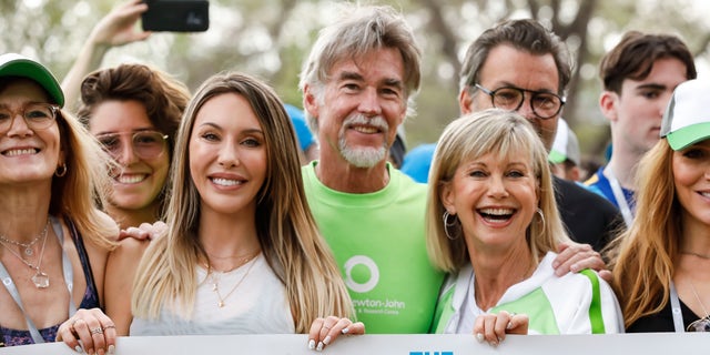 Su hija Chloe Latanzi, izquierda, y su esposo John Easterling, centro, apoyan a Olivia Newton-John, derecha, en 2019 en su caminata anual en el Centro de Investigación y Bienestar del Cáncer en Australia.
