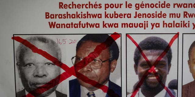 A red cross is seen drawn on the face of Augustin Bizimana (R), one of the most-wanted fugitives from the 1994 Rwandan genocide, next to the red-crossed face of Felicien Kabuga (L), who was arrested last week in Paris, on a wanted poster at the Genocide Fugitive Tracking Unit office in Kigali, Rwanda, on May 22, 2020.