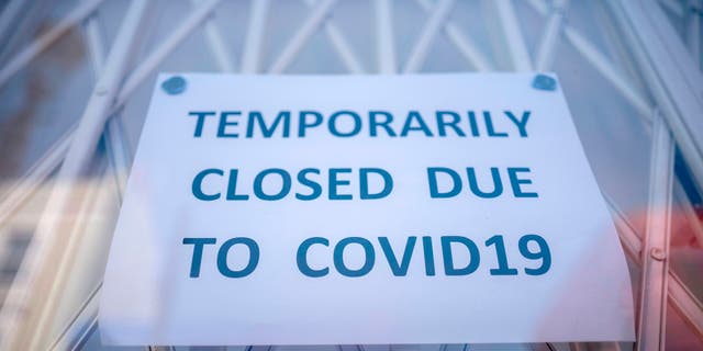 A sign is seen in the window of a shop explaining to customers that it has temporarily closed due to the coronavirus outbreak in Portobello Market in west London. (Photo by TOLGA AKMEN/AFP via Getty Images)