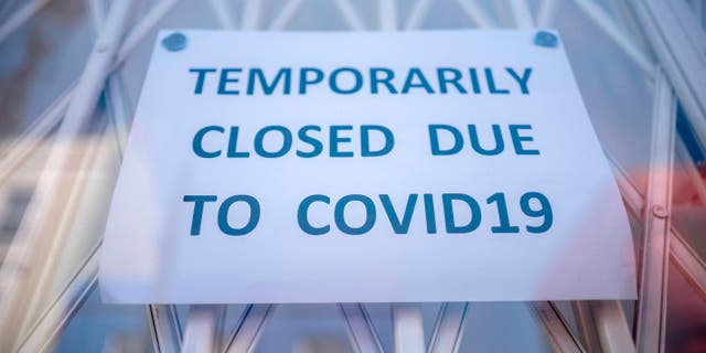 A sign is seen in the window of a shop explaining to customers that it has temporarily closed due to the coronavirus outbreak in Portobello Market in west London. (Photo by TOLGA AKMEN/AFP via Getty Images)