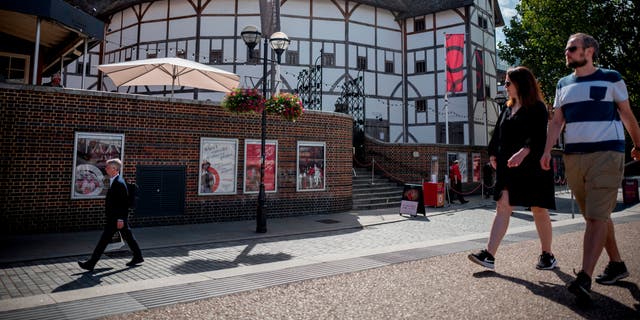مردم در 24 اوت 2020 از کنار تئاتر شکسپیر گلوب در مرکز لندن عبور می کنند. 