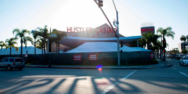 The sun casts the shadows of the Hustler Casino sign onto the road.