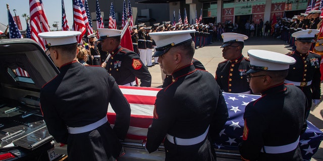 A military honor guard carries the flag-draped casket of Marine Lance Cpl. Kareem Grant Nikoui at the Harvest Christian Fellowship on Sept. 18, 2021, in Riverside, California.