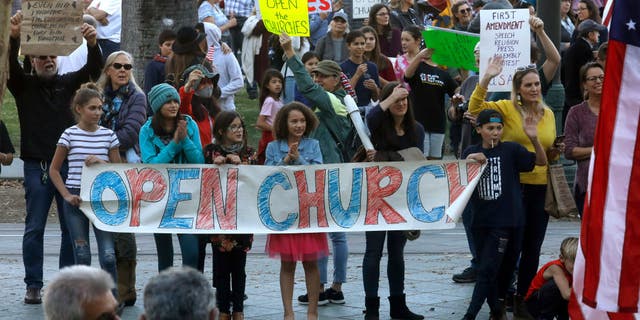 Supporters of Calvary Chapel San Jose wave to cars outside of Santa Clara Superior Court in downtown San Jose, California, Dec. 8, 2020.