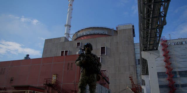 Russian military personnel stand guard outside the second reactor of the Zaporizhia nuclear power plant in Energodar, May 1, 2022. 