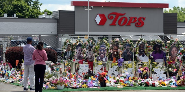 Community members pay respects at a memorial filled with flowers, photos and mementos outside the Tops Friendly Market on Jefferson Avenue on July 14, 2022, in Buffalo, New York.