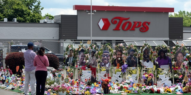 Community members pay respects at a "Memorial Garden" filled with flowers, photos and mementos outside the Tops Friendly Market on Jefferson Avenue on July 14, 2022, in Buffalo, New York.