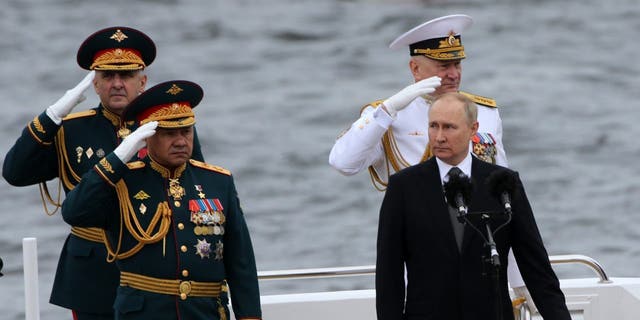 Russian President Vladimir Putin, front right, Defense Minister Sergei Shoigu, left, and Russian Fleet Commander Nikolai Yevmenov, back right, aboard a boat during the Navy Day Parade, July 31 2022, in St. Petersburg, Russia.