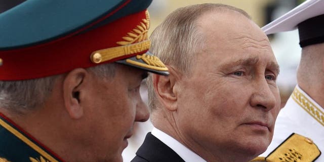 Russia's President Vladimir Putin sits next to Russia's Defense Minister Sergei Shoigu (L) as he takes part in the main naval parade marking the Russian Navy Day, in St.  Petersburg on July 31, 2022. 