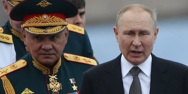 Владимир Путин и его министр обороны Сергей Шойгу стоят вместе во время парада в честь Дня Военно-морского флота в Санкт-Петербурге, Россия, июль.