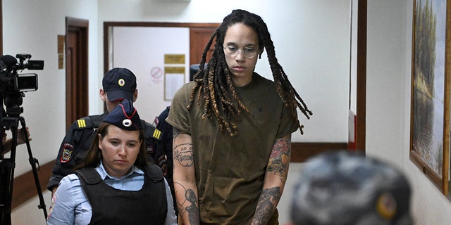 Brittany Griner is escorted by police ahead of a hearing in Russia.