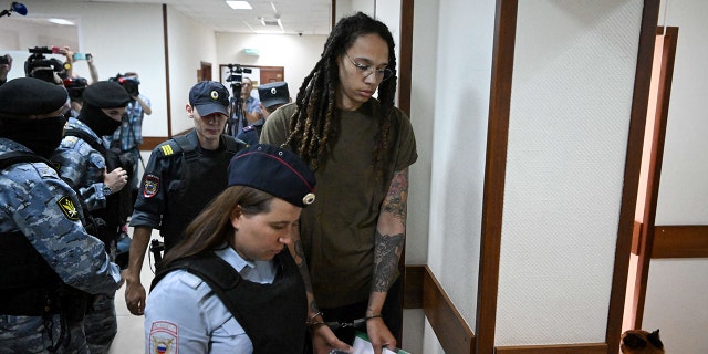 U.S. basketball player Brittney Griner (R) is escorted by police before a hearing during her trial on charges of drug smuggling, in Khimki, outside Moscow on Aug. 2, 2022.