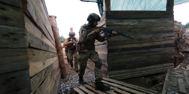 KHARKIV REGION, UKRAINE - AUGUST 3, 2022 - Armed National Guard soldiers walk along a trench in one of the sections of the defensive line outside Kharkiv in the Kharkiv region of northeastern Ukraine. 