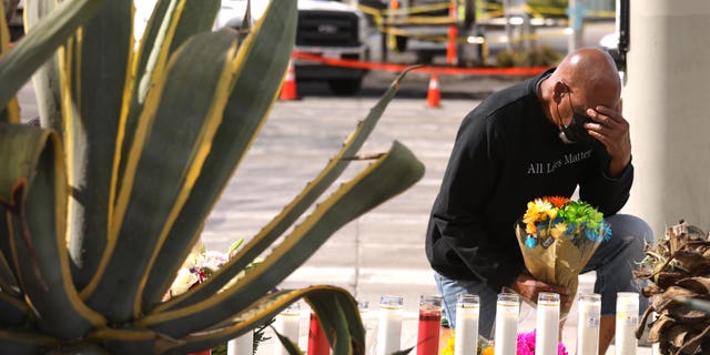 London Carter, with Southern Missionary Baptist Church, prays over a makeshift memorial across the street from where a fiery multi-car crash left six dead, including a pregnant woman, and injured others in Windsor Hills in Los Angeles.