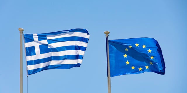 Flags of Greece and Europe on a flagpole waving in the wind. The flag of Europe on a flagpole waving in the blue sky during a summer sunny day at the Greek capital city Athens. The flag of Europe or the European Flag is the symbol of the Council of Europe CoE and The European Union EU. The national flag of Greece, Flag of the Hellenic Republic or Greek flag with the White and Blue colors symbolise the Greek sky and sea named as Galanolefki meaning The Blue and White. The Greek flag as seen on a flagpole waving in the blue sky during a summer sunny day at the Greek capital city Athens. July 2022 (Photo by Nicolas Economou/NurPhoto via Getty Images)