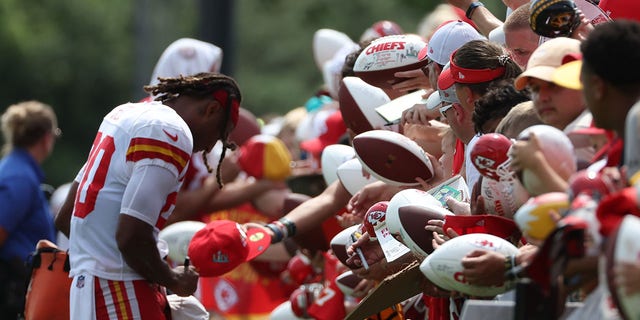 Fans hold a football for safety as Justin Reid, 20, signs after training camp at Missouri Western State University in St. Joseph, Missouri on August 7, 2022. 