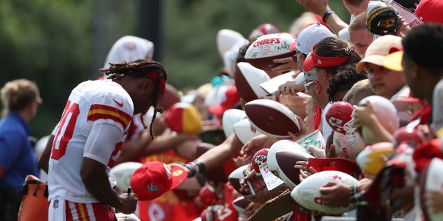 Fans hold a football for safety as Justin Reid, 20, signs after training camp at Missouri Western State University in St. Joseph, Missouri on August 7, 2022. 