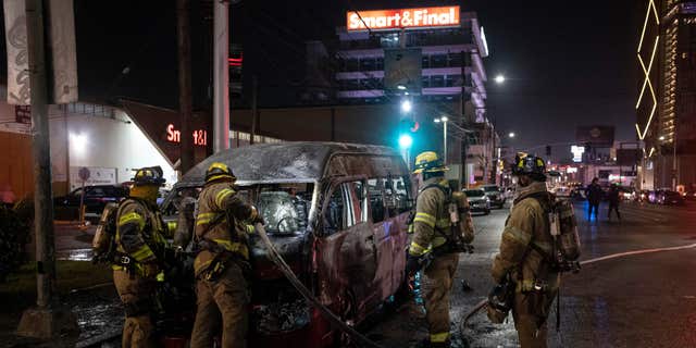소방관들이 2022년 8월 12일 멕시코 바하칼리포르니아주 티후아나에서 신원 미상의 개인들에 의해 불에 탄 집단 수송 차량의 현장에서 작업하고 있다. 