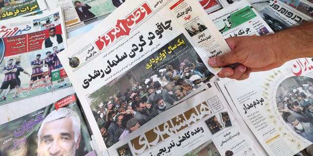 A man shows today's edition of the Iranian newspaper Vatan-e Emrooz with a front page headline in Farsi — "Knife in the neck of Salman Rushdie" — in the capital Tehran Aug. 13, 2022.