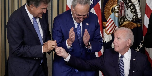 President Joe Biden (R) gives Sen. Joe Manchin (D-WV) (L) the pen he used to sign The Inflation Reduction Act