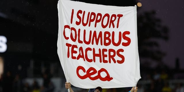 A Nordecke capo holds a sign in support of Columbus teachers who are voting whether to go on strike in a match between the Columbus Crew and Atlanta United Aug. 21, 2022, at Lower.com Field in Columbus, Ohio.  