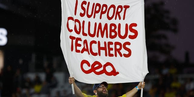 A Nordecke capo holds a sign in support of Columbus teachers who are voting whether to go on strike in a match between the Columbus Crew and Atlanta United Aug. 21, 2022, at Lower.com Field in Columbus, Ohio.