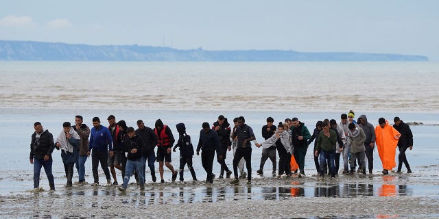 A group of people, thought to be migrants, walk ashore in Dungeness, Kent, following a small boat incident in the Channel Aug. 25, 2022.