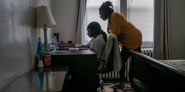 A student takes part in remote learning on a Chromebook with the help of her mom at home on October 28, 2020, in Stamford, Connecticut. 