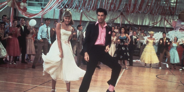Olivia Newton-John and John Travolta dance in a crowded high school gym in a still from the 1978 Paramount film "Grease."