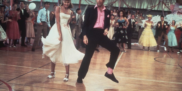 Olivia Newton-John and John Travolta dance in a crowded high school gym in a still from the 1978 Paramount film "Grease."