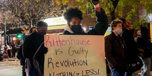 A protester holds a "Rittenhouse is guilty" sign while raising her fist during a protest against the acquittal of Kyle Rittenhouse in the West Village on November 19, 2021, in New York City. 