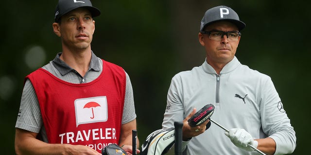 Rickie Fowler talks with his caddy Joe Skovron during a practice round before the Travelers Championship at TPC River Highlands on June 22, 2022 in Cromwell, Connecticut.