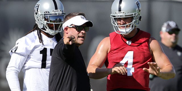 Wide receiver Davante Adams, #17, head coach Josh McDaniels and quarterback Derek Carr #4 of the Las Vegas Raiders talk during training camp at the Las Vegas Raiders Headquarters/Intermountain Healthcare Performance Center on July 24, 2022, in Henderson, Nevada.