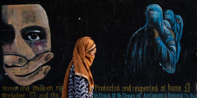 A woman walks past a mural calling for women and children's rights in Afghanistan on August 12, 2022 in Bamian, Afghanistan. 