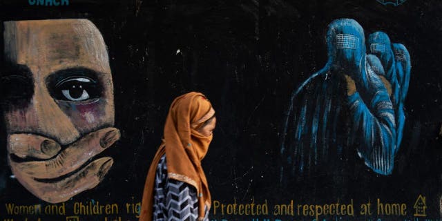 A woman walks past a mural calling for the rights of women and children in Afghanistan on August 12, 2022 in Bamian, Afghanistan.