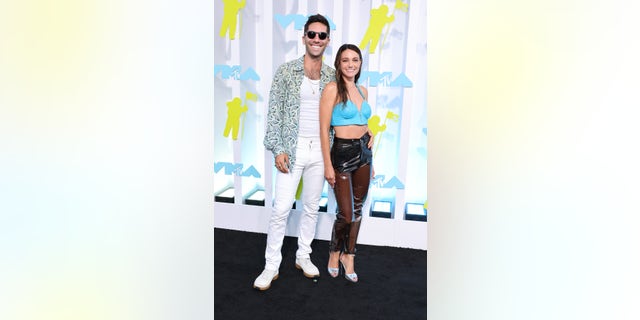 Nev Schulman wore white pants and a white shirt with a peace sign button, while Laura Perlongo wore a blue top and slacks at the VMAs.