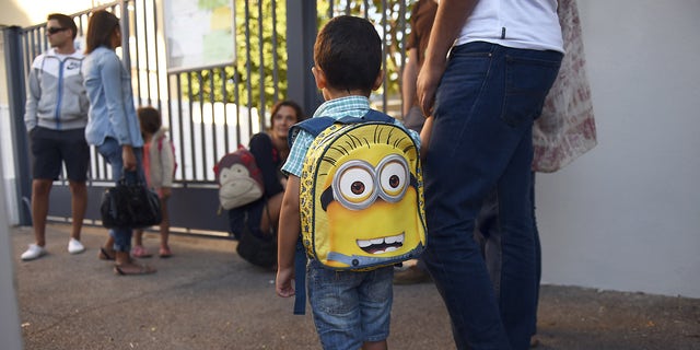 A child wearing a schoolbag is accompanied to his elementary school on September 2, 2014, at the start of a new school year.
