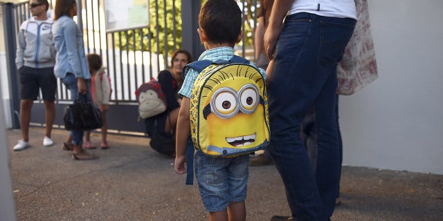 A child wearing a schoolbag is accompanied to his elementary school on September 2, 2014, at the start of a new school year.