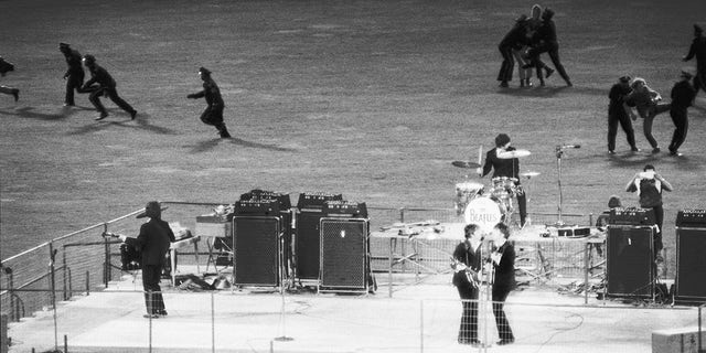 Policemen clear the field of enthusiastic fans as The Beatles perform on a bandstand in Candlestick Park, San Francisco, California, on Aug. 29, 1966.