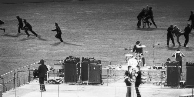 Policemen clear the field of enthusiastic fans as The Beatles perform on a bandstand in Candlestick Park, San Francisco, California, on Aug. 29, 1966.