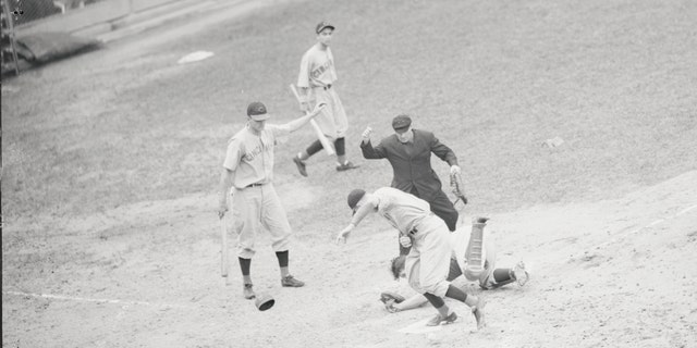 The first televised baseball game, August 26, 1939. Bucky Walters of the Cincinnati Reds pitched a two-hit game against the Brooklyn Dodgers and helped himself along by scoring one of the Reds' run in the big eighth inning. The Reds scored all of their runs in the eighth inning to beat the Dodgers, 5-2. Walters is shown scoring here, as Dodgers' catcher Babe Phelps rolls in the dirt after dropping the ball.