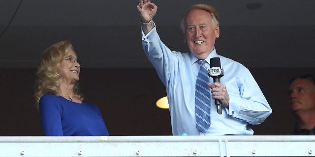 Los Angeles Dodgers broadcaster Vin Scully waves to the crowd alongside his wife Sandra Hunt before the Dodgers take on the Chicago Cubs in game five of the National League Division Series at Dodger Stadium on Oct. 20, 2016 in Los Angeles.