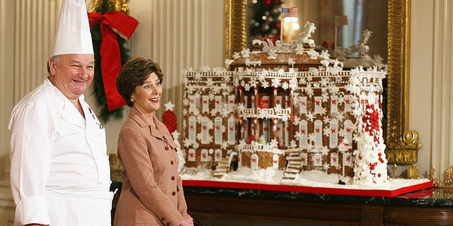 Then-first lady Laura Bush stands with guest pastry chef Roland Mesnier while talking about the gingerbread White House creation he made for the State Dining Room during a media preview of the 2006 holiday decorations at the White House on Nov. 30, 2006, in Washington, D.C. 