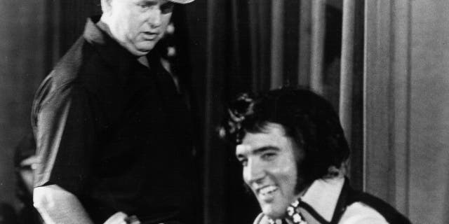 Elvis Presley is seen holding court at a press conference to publicize his show at Madison Square Garden later that night while Colonel Tom Parker looks on at the Hilton Hotel on June 9, 1972, in New York City.