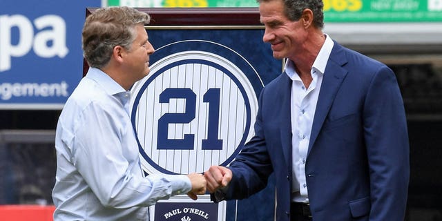 New York Yankees former player Paul O'Neill fist bumps owner Hal Steinbrenner during a ceremony to retire his number before the game between the New York Yankees and Toronto Blue Jays at Yankee Stadium August 21, 2022, in New York.